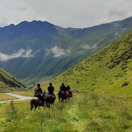 Gruppe von Reitern in einem sonnigen Tal in Tuschetien im Kaukasus